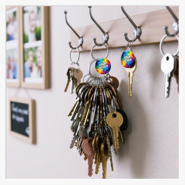 Zwei 32 mm Button als Schlüsselanhänger vor einem Schlüsselbrett