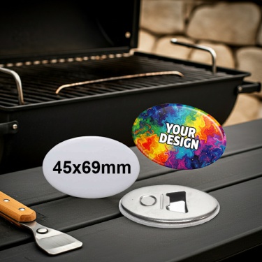 Ein ovaler Button mit der stabilen Metall-Öffner-Funktion und dem integrierten Magneten vor einem BBQ-Grill.